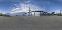 the view of a large bridge from below with a blue sky background and clouds over it