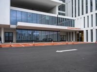 a white and grey building with orange construction cones on it's pavement on the sidewalk