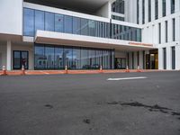 a white and grey building with orange construction cones on it's pavement on the sidewalk