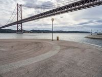 there is a view of the bridge from the beach in spain under it, and it's almost empty