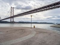 there is a view of the bridge from the beach in spain under it, and it's almost empty