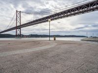 there is a view of the bridge from the beach in spain under it, and it's almost empty