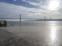 the sky is partly cloudy over the bridge and water near the ocean flooring stone walkway