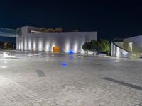 several benches and benches in the open with lights at night on their legs near buildings