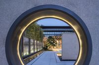 an outdoor walkway surrounded by a concrete circle with lights and plants lit up in the corner