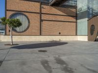 an umbrella is sitting on the concrete outside of a building with a glass facade on a sunny day