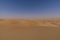 the woman is flying her kite in the desert with no clouds behind herself of course