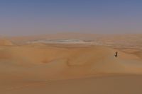 the woman is flying her kite in the desert with no clouds behind herself of course