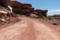 there is a dirt road leading into a desert area with rock formations in the distance