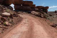 there is a dirt road leading into a desert area with rock formations in the distance