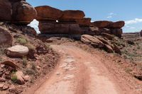 there is a dirt road leading into a desert area with rock formations in the distance