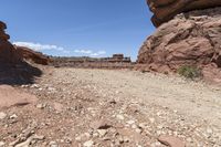 a dirt road in a desert area next to some rocks and boulders on a sunny day