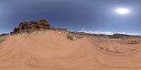 a red desert with two big rocks in the distance and some mountains on the horizon