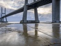 a very big bridge over some water near a beach in the ocean with an umbrella