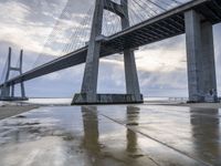 a very big bridge over some water near a beach in the ocean with an umbrella