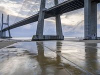 a very big bridge over some water near a beach in the ocean with an umbrella