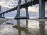 a very big bridge over some water near a beach in the ocean with an umbrella