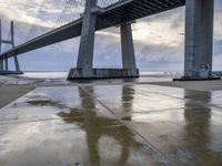 a very big bridge over some water near a beach in the ocean with an umbrella