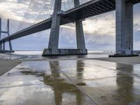 a very big bridge over some water near a beach in the ocean with an umbrella