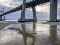 a very big bridge over some water near a beach in the ocean with an umbrella