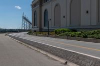 there is a lone bird sitting on the curb next to the road and a bridge