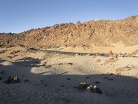 a lone black truck on the side of a desert road near a mountain and sign