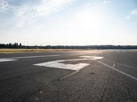 a lone jet landing on the runway at the airport as sun hits in the sky