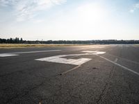 a lone jet landing on the runway at the airport as sun hits in the sky