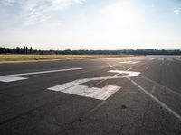 a lone jet landing on the runway at the airport as sun hits in the sky