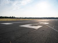 a lone jet landing on the runway at the airport as sun hits in the sky