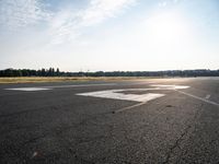 a lone jet landing on the runway at the airport as sun hits in the sky