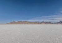 a lone motorcycle is on a deserted plain in the desert with some mountains behind it