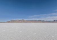 a lone motorcycle is on a deserted plain in the desert with some mountains behind it