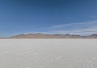 a lone motorcycle is on a deserted plain in the desert with some mountains behind it