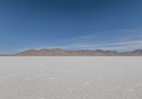 a lone motorcycle is on a deserted plain in the desert with some mountains behind it