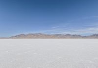 a lone motorcycle is on a deserted plain in the desert with some mountains behind it