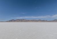 a lone motorcycle is on a deserted plain in the desert with some mountains behind it