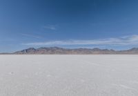 a lone motorcycle is on a deserted plain in the desert with some mountains behind it