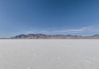 a lone motorcycle is on a deserted plain in the desert with some mountains behind it