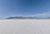 a lone motorcycle is on a deserted plain in the desert with some mountains behind it