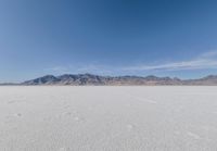 a lone motorcycle is on a deserted plain in the desert with some mountains behind it