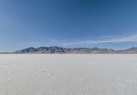 a lone motorcycle is on a deserted plain in the desert with some mountains behind it