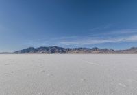 a lone motorcycle is on a deserted plain in the desert with some mountains behind it