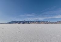 a lone motorcycle is on a deserted plain in the desert with some mountains behind it