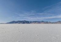 a lone motorcycle is on a deserted plain in the desert with some mountains behind it