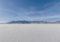 a lone motorcycle is on a deserted plain in the desert with some mountains behind it