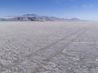 there is a lone motorcycle parked in the desert, with mountains in the background, and no one on the side