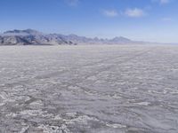 there is a lone motorcycle parked in the desert, with mountains in the background, and no one on the side