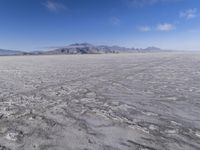 there is a lone motorcycle parked in the desert, with mountains in the background, and no one on the side