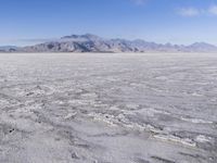 there is a lone motorcycle parked in the desert, with mountains in the background, and no one on the side